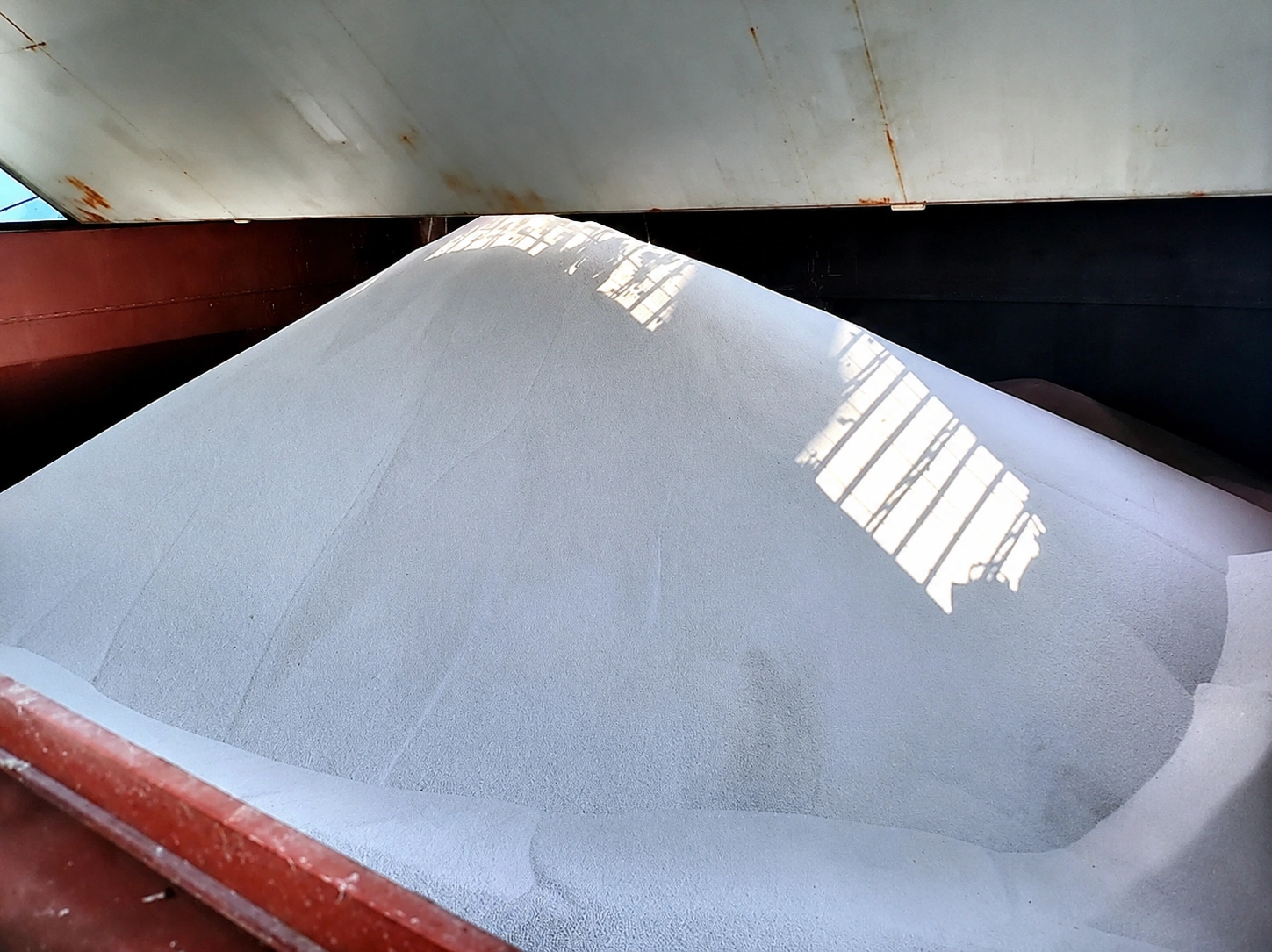 White bulk cargo stockpiled inside an open ship hold