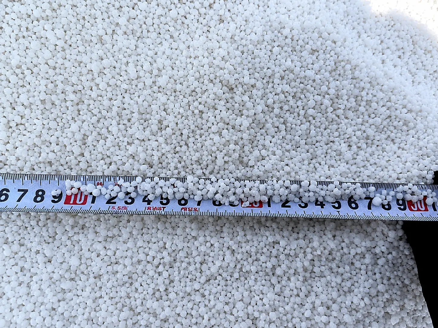 White granular product inspected against a measuring tape